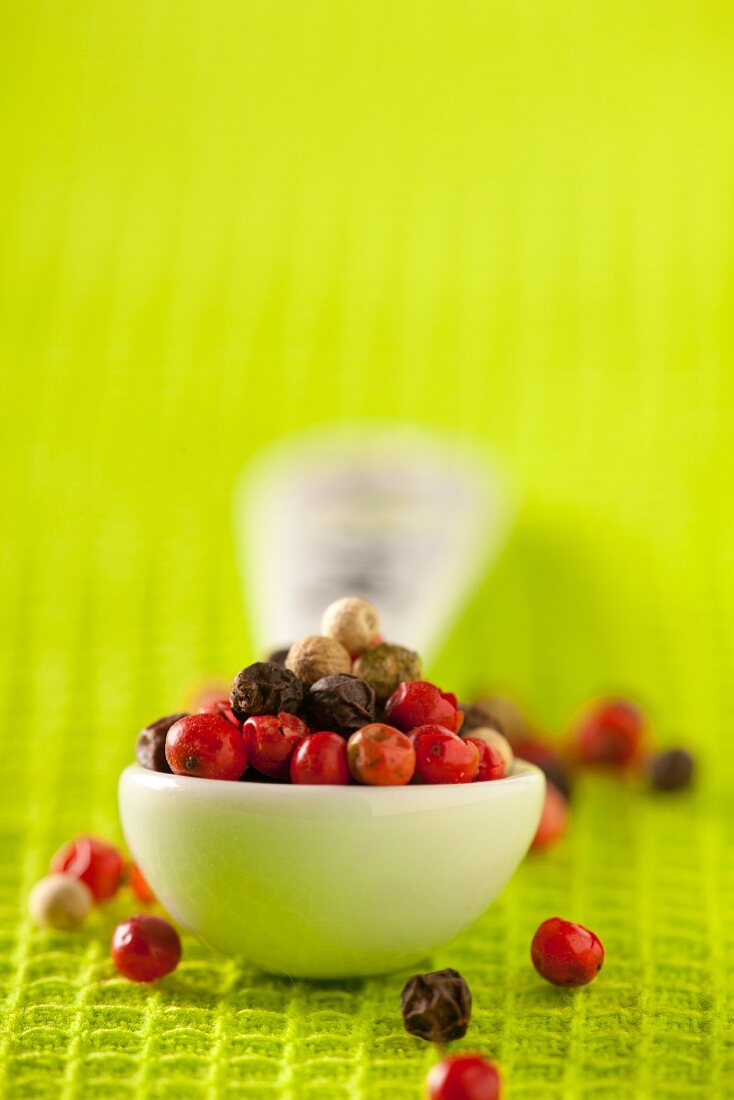 Various different coloured peppercorns on a spoon