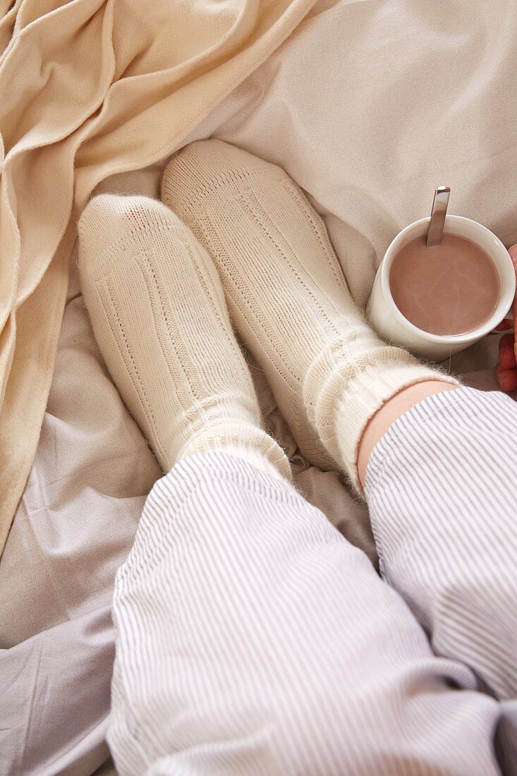 Feet in warm bed socks and a cup of cocoa in bed
