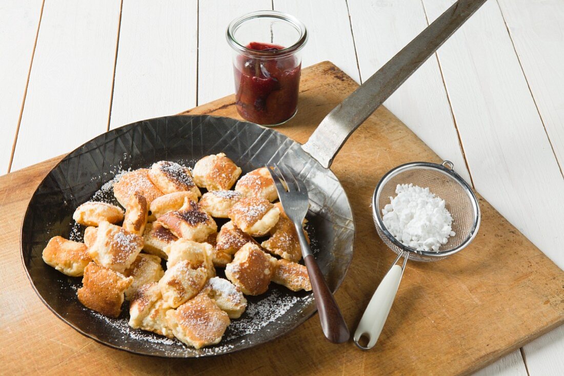 Pan of shredded pancake with damson compote and icing sugar