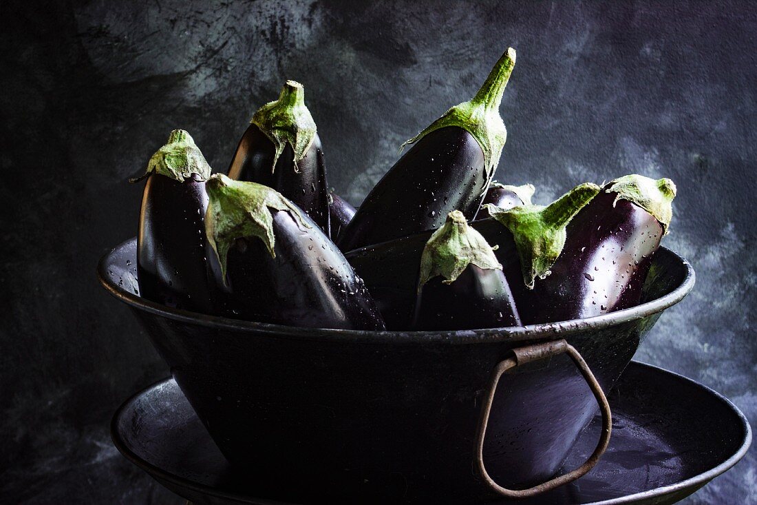 Fresh aubergines in a metal bowl