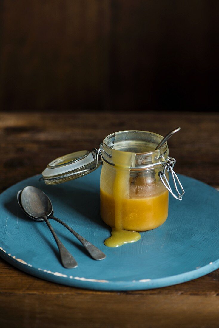 Caramel sauce in an open flip-top jar with antiques spoons next to it