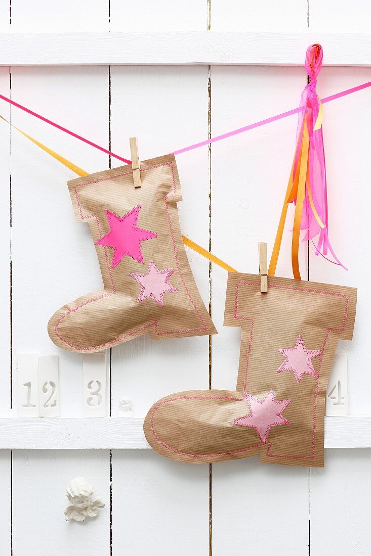 Nikolausstiefel aus Packpapier mit Wäscheklammern an Geschenkbändern als Adventskalender