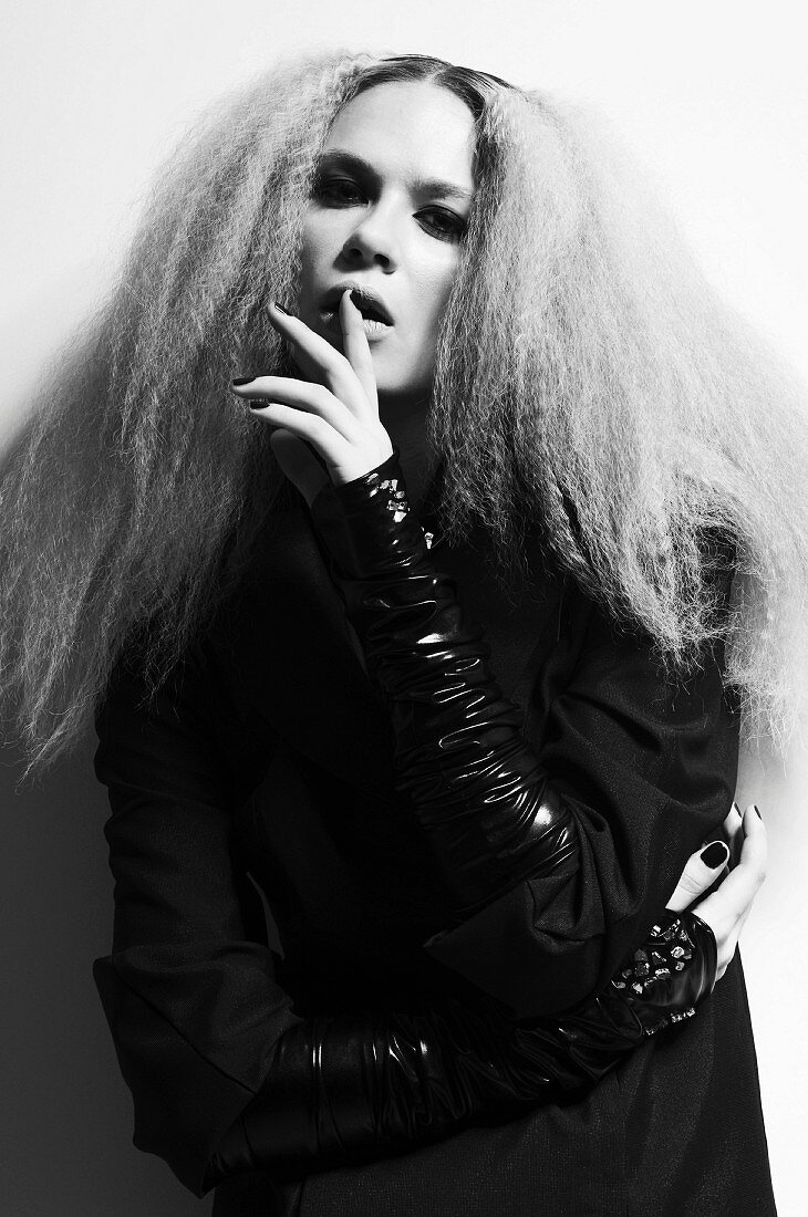A young woman with crimped hair wearing a black outfit (black-and-white shot)