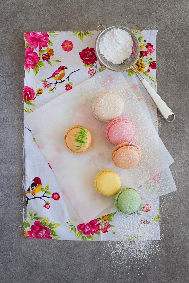 Various macaroons on a piece of paper with icing sugar