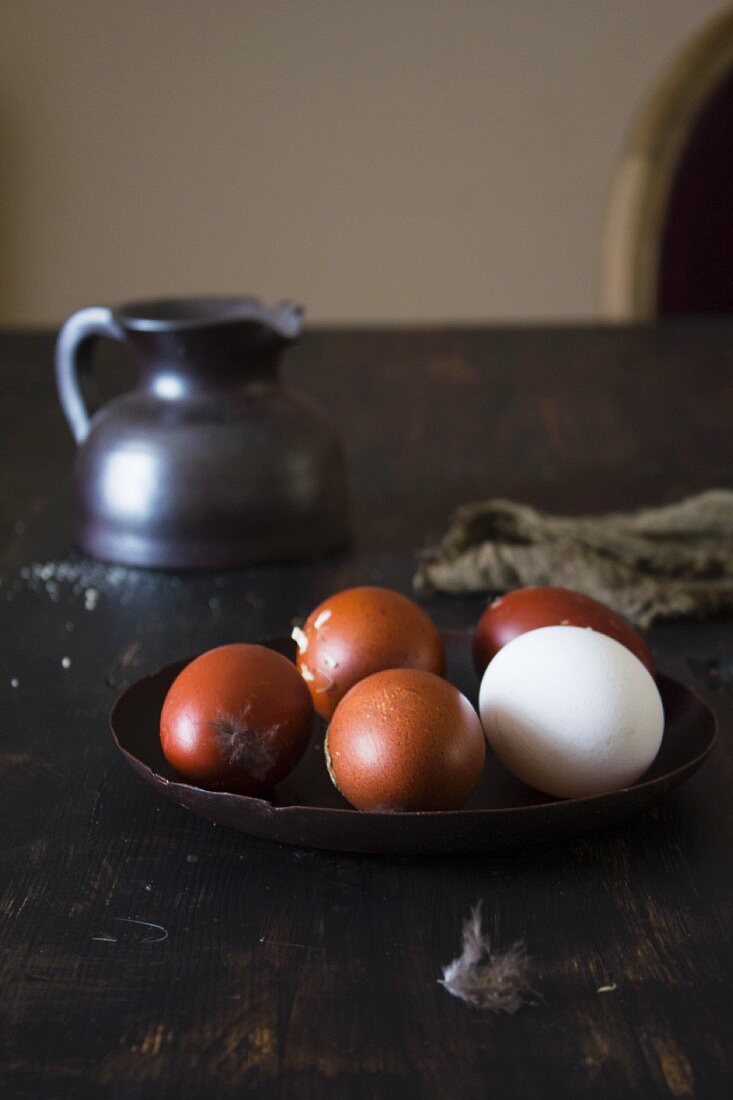 Brown eggs and one white egg with feathers