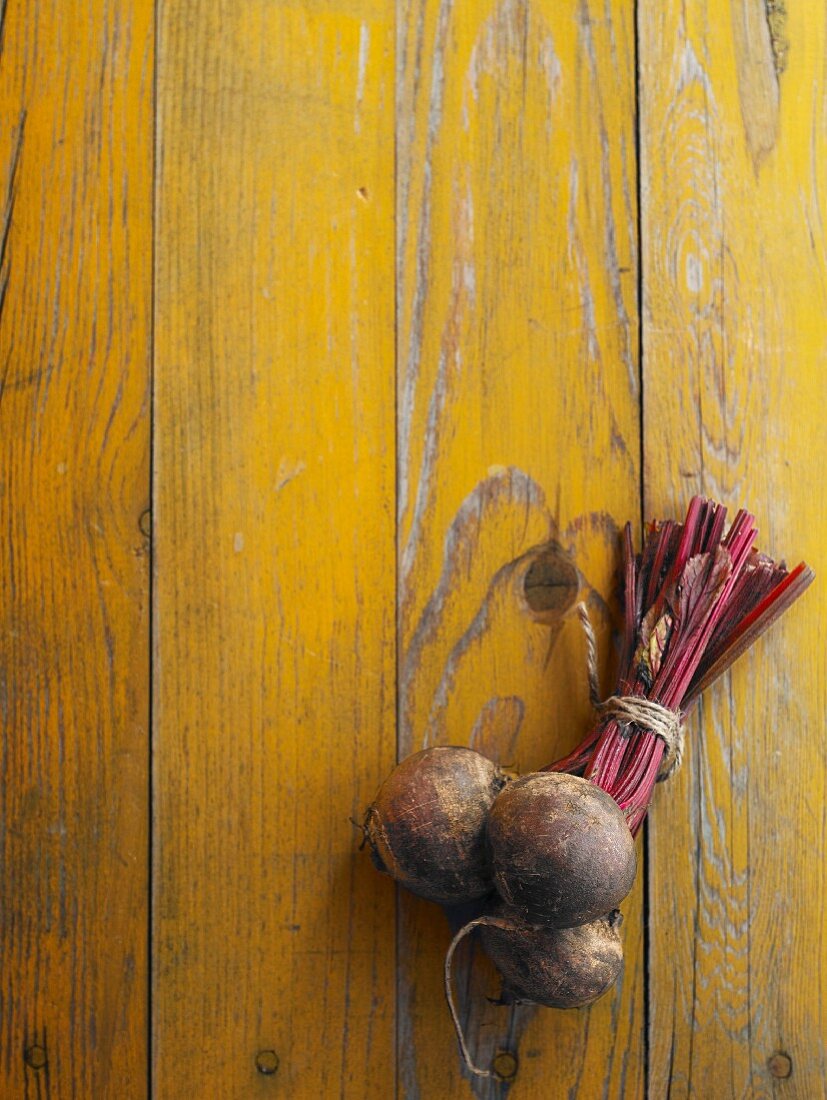 A bundle of beetroot on a yellow wooden table