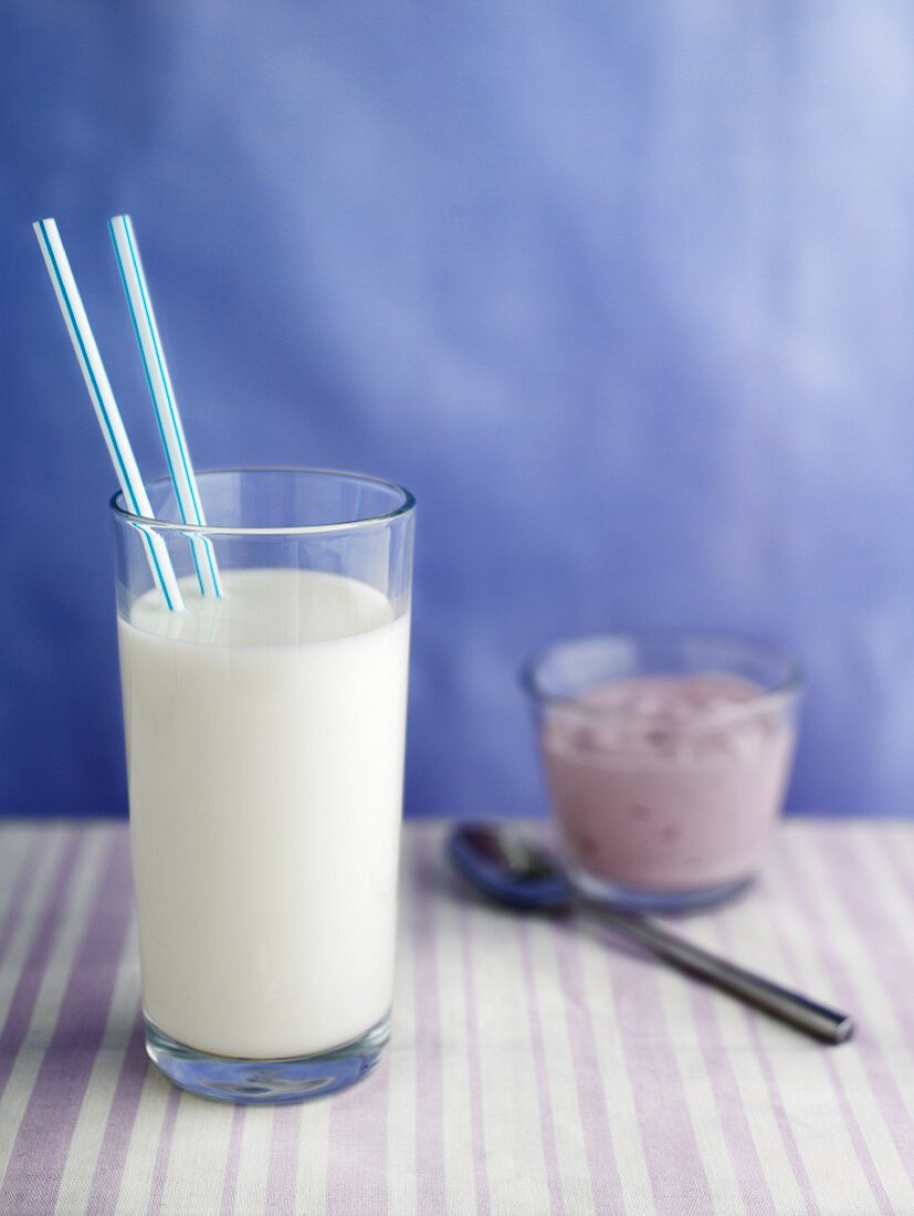 A glass of milk with two straws