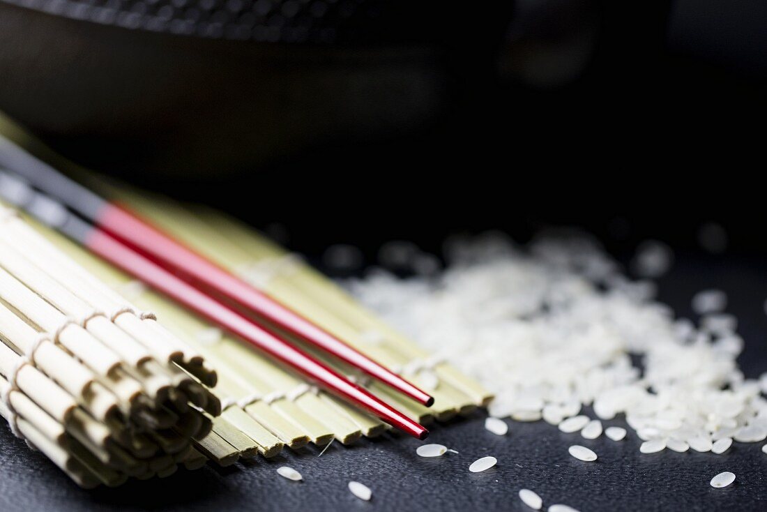 An arrangement featuring chopsticks, a bamboo mat and rice (Asia)