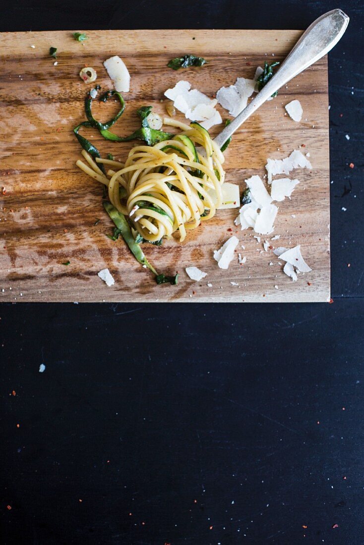 Linguine with courgettes, spinach and Parmesan cheese on a fork (seen from above)