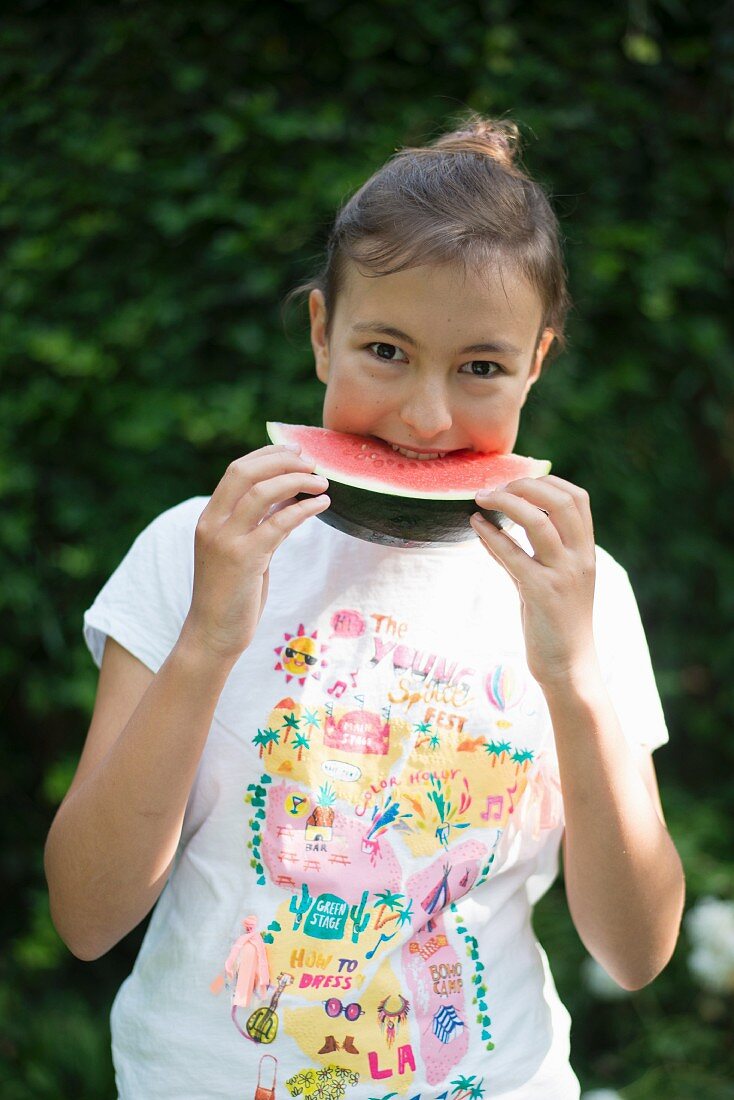 Girl eating watermelon in garden