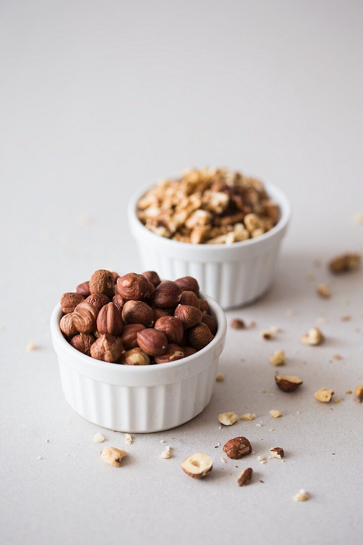 Hazelnuts and walnuts in two white ceramic bowls