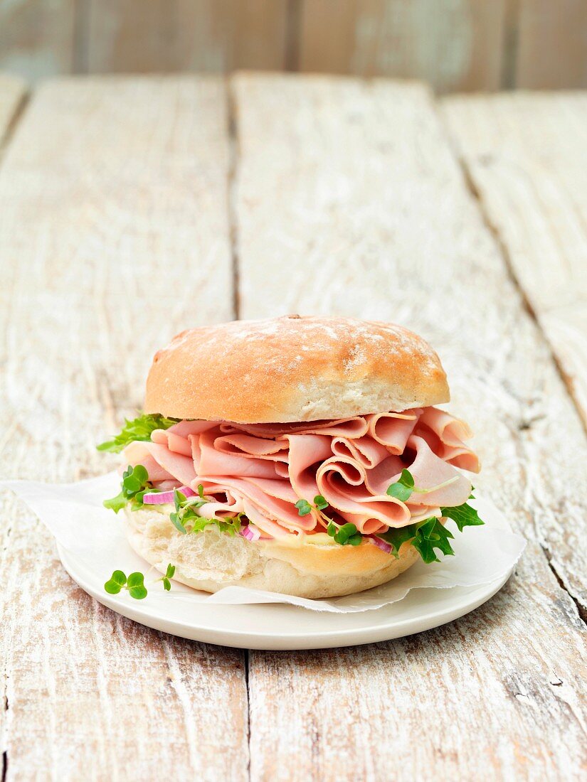 Wafer thin smoked ham on a roll with leafy vegetables