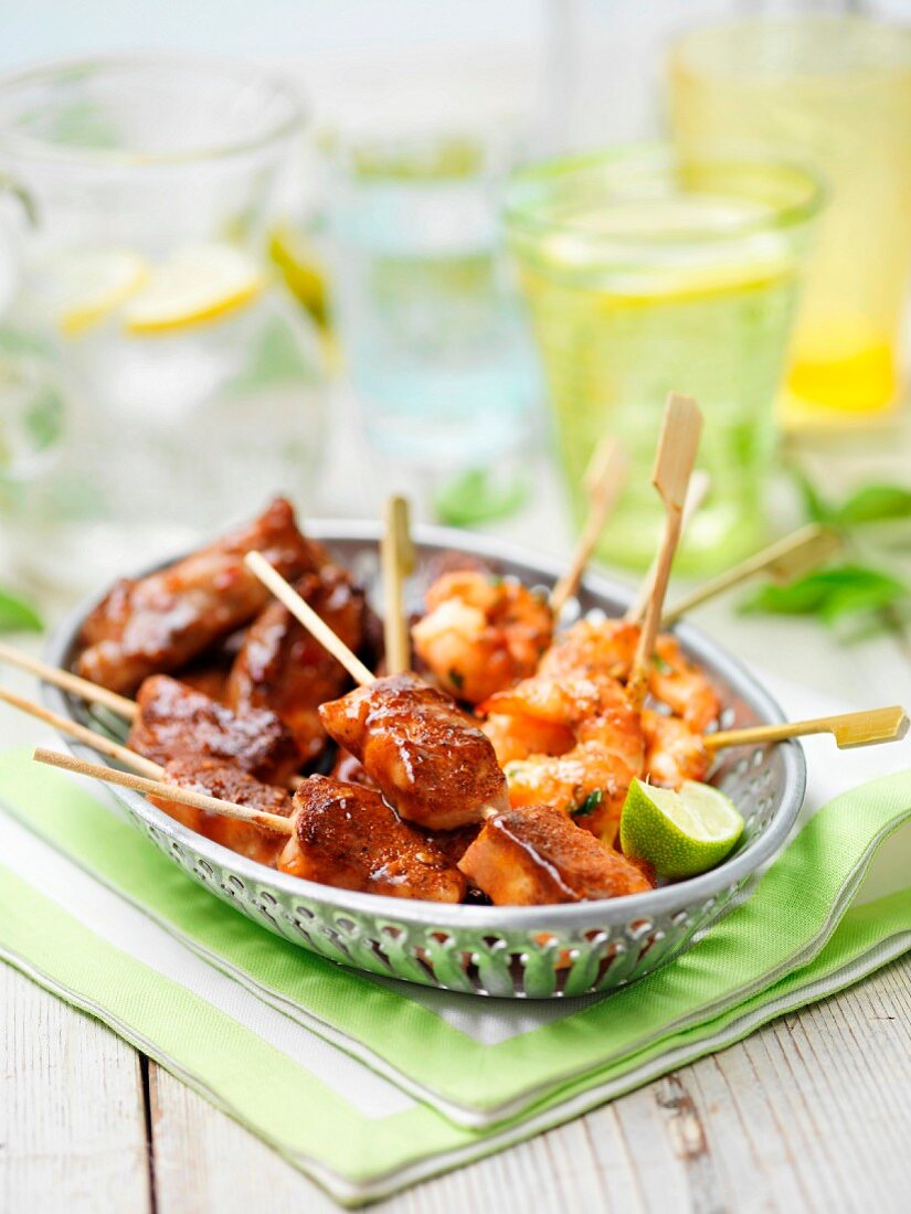 A mini grill selection featuring king prawns, chicken wings and pork in a vintage basket on a garden table