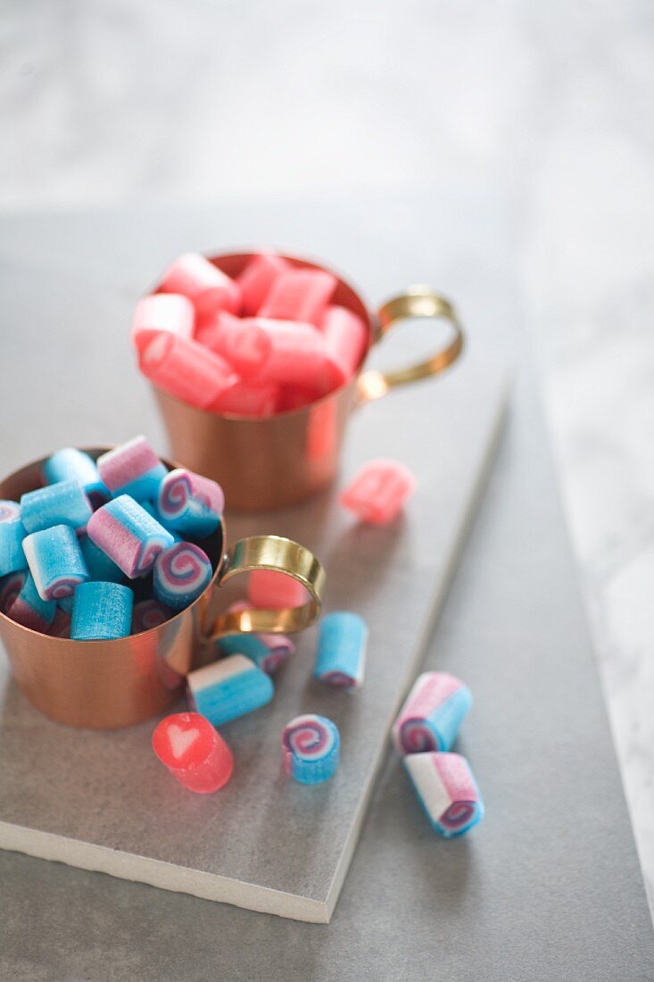 Blaue & rosafarbene Bonbons in Kupfertassen