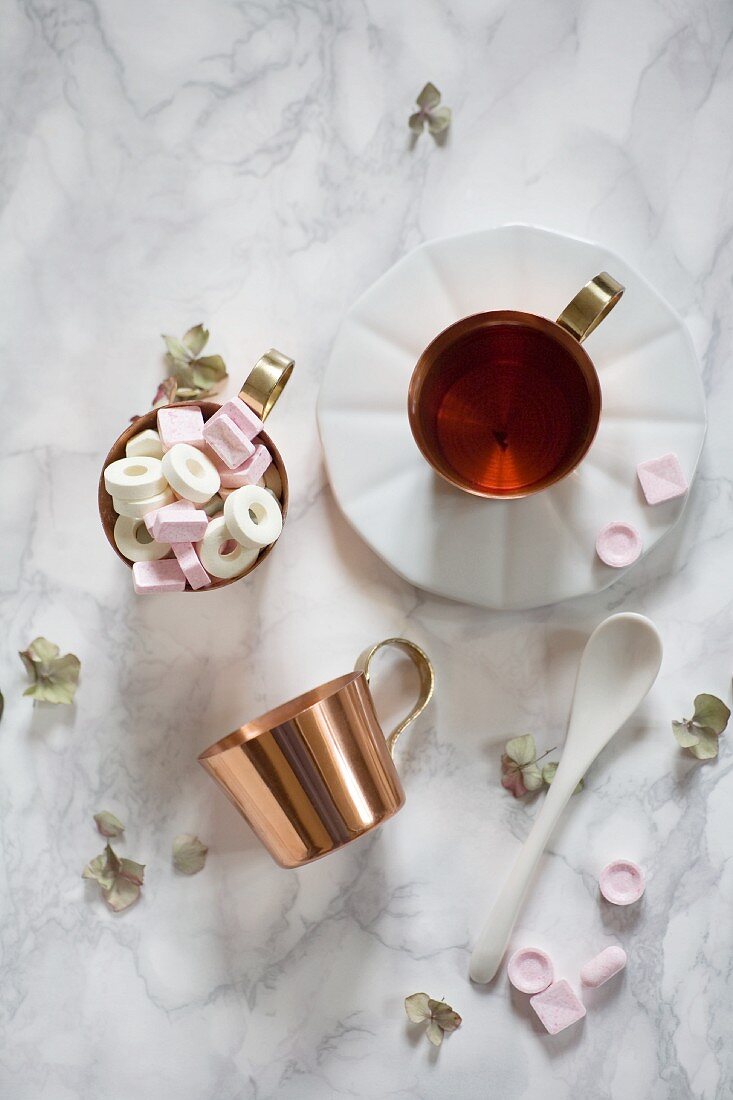 An arrangement of tea and grape sugar sweets in a copper cup