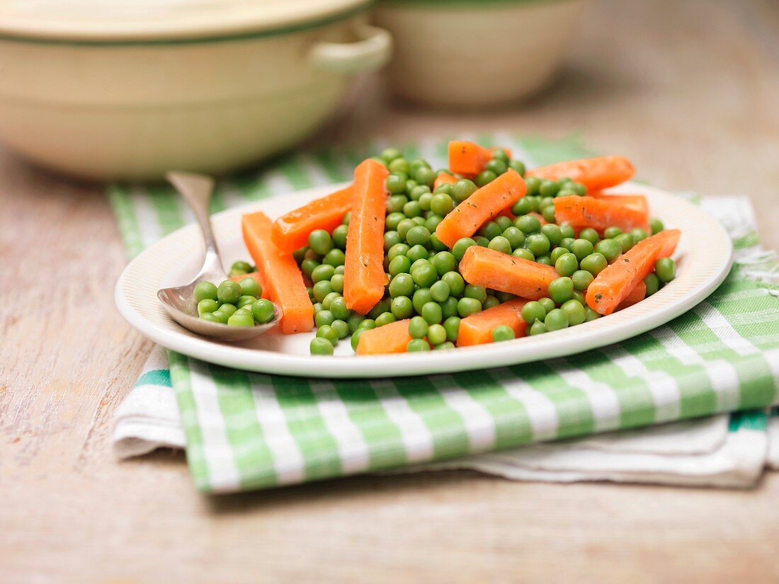 A plate of peas and carrots with mint and butter on a tea towel