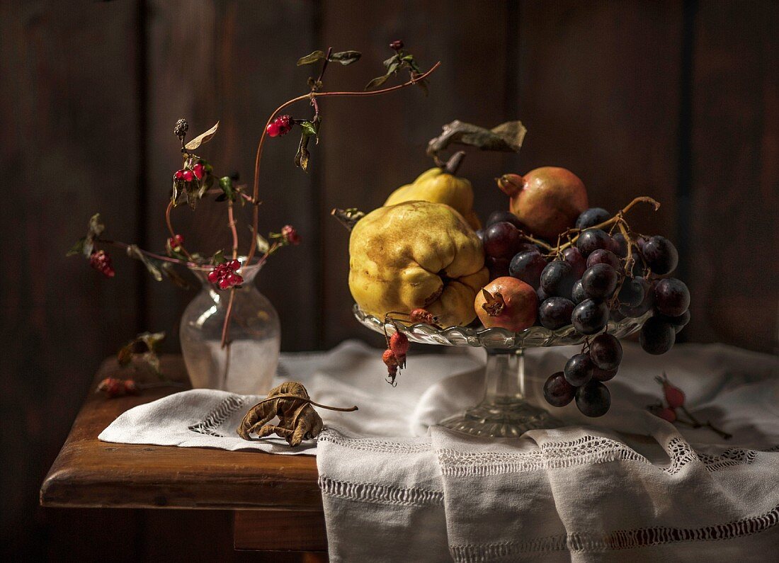 An autumnal arrangement of fruit featuring qunices, grapes and pomegranate seeds