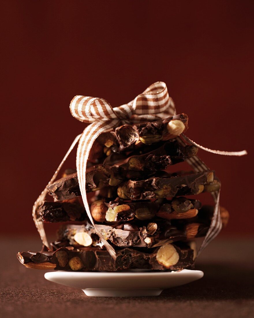 A stack of broken chocolate with nuts tied with a ribbon