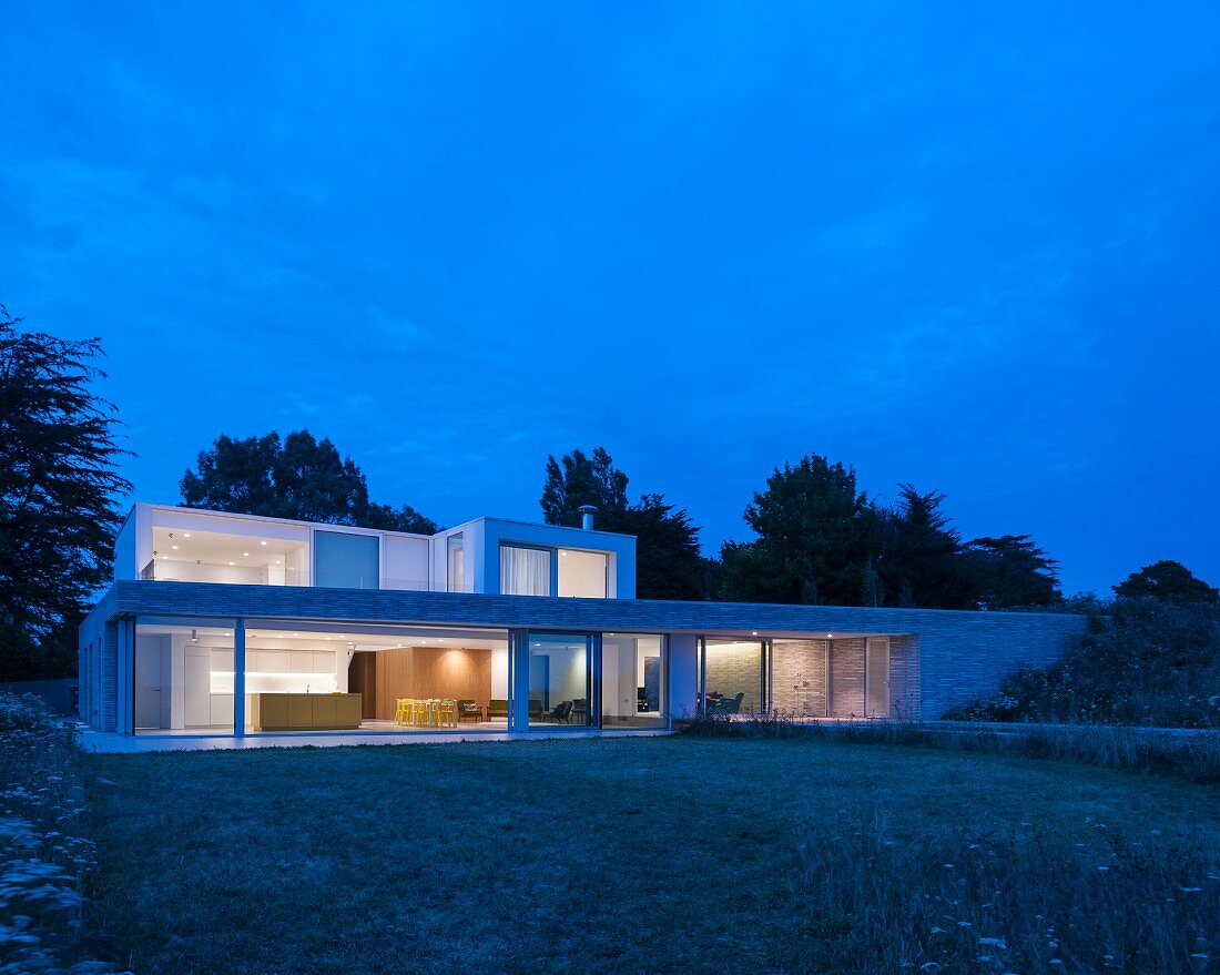 Modern architect-designed house with flat roofs and large windows at twilight