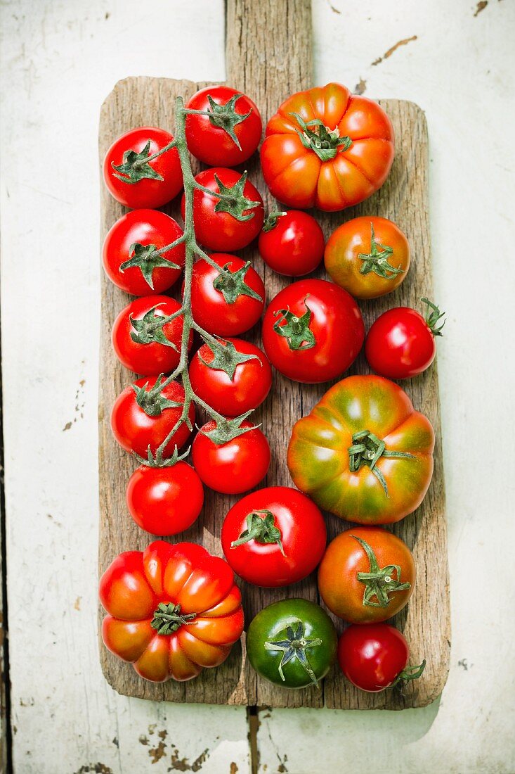 Various types of tomatoes on a wooden board