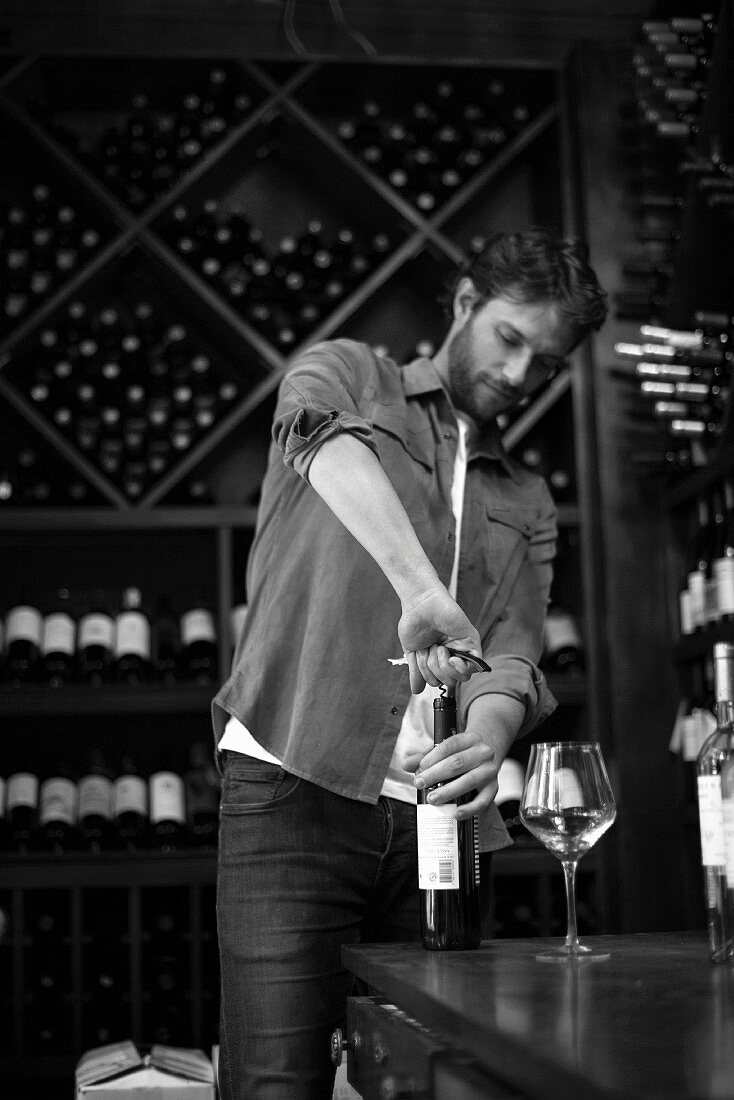 A sommelier opening a bottle of wine (black and white shot)