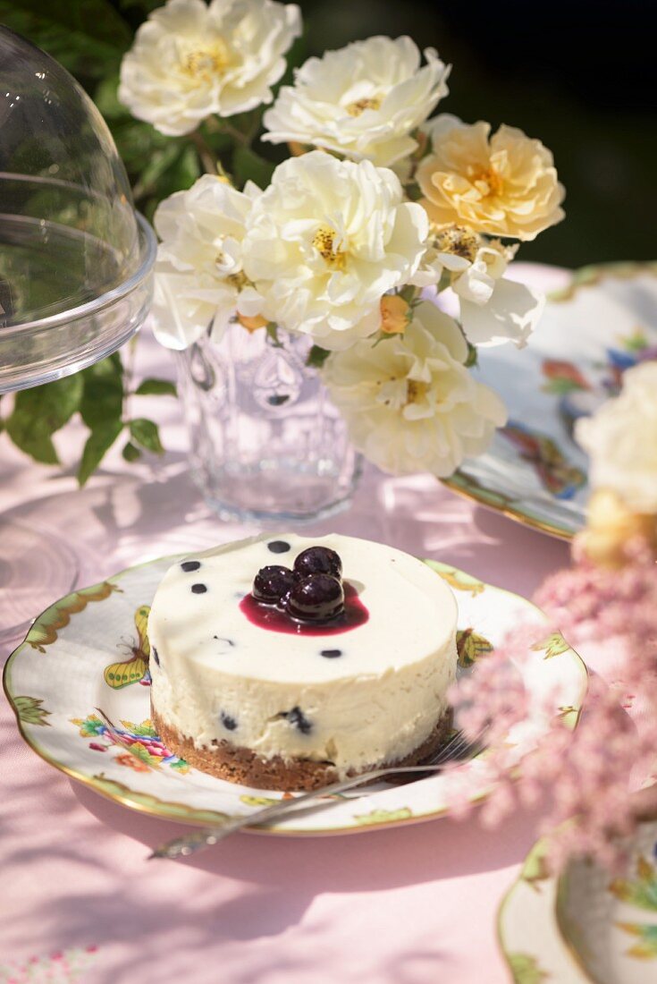 A small cheesecake with blueberries on the garden table