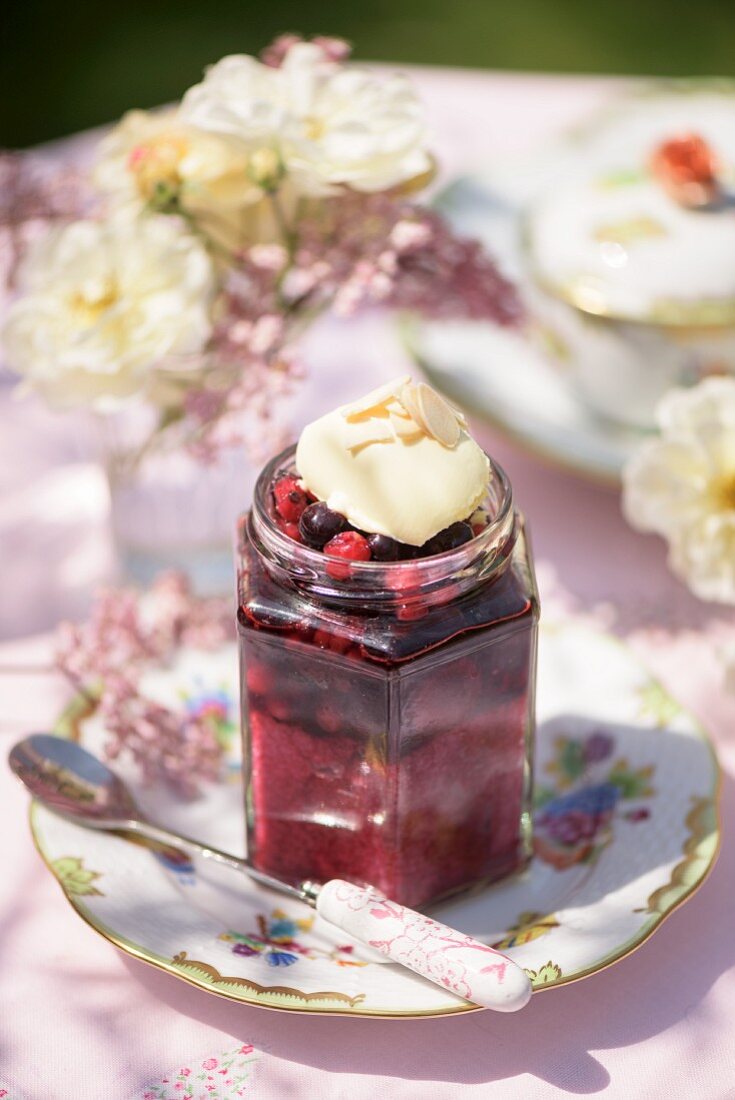 A jar of berry jam on a garden table