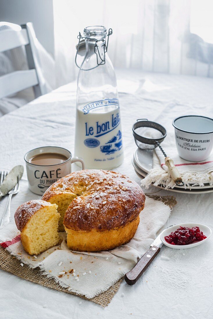 Französisches Frühstück mit Café Au Lait, Brioche, Konfitüre und einer Flasche Milch