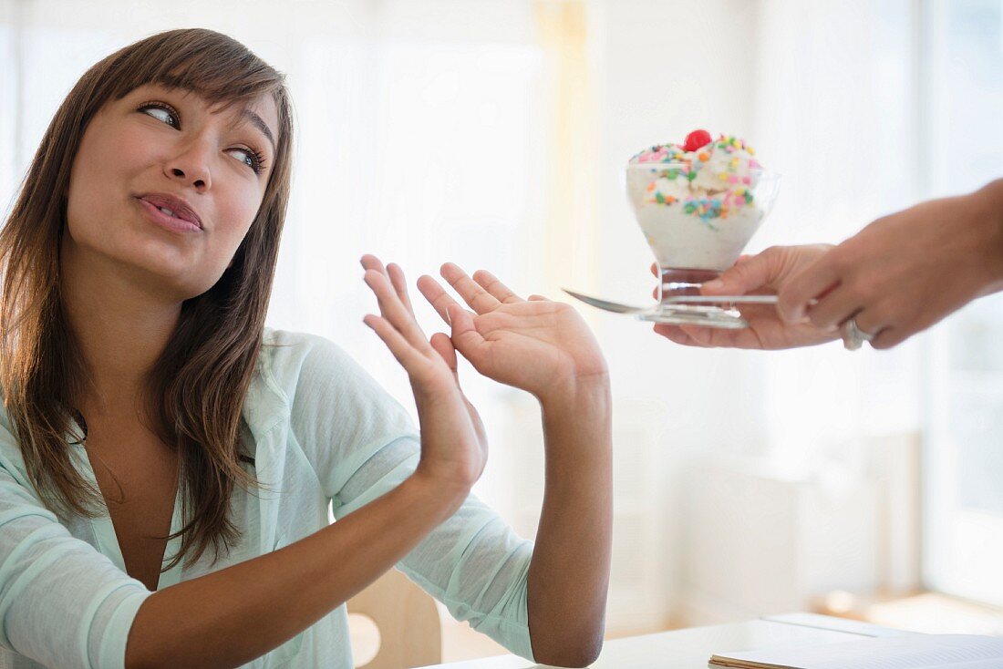 A young woman refusing an ice cream sundae