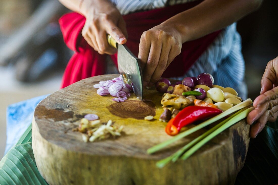 A cook cutting oriental ingredients on chopping board