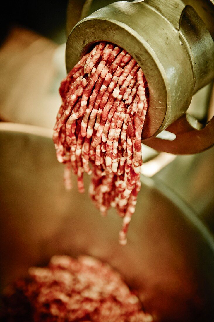 Freshly minced meat in a meat grinder (close-up)