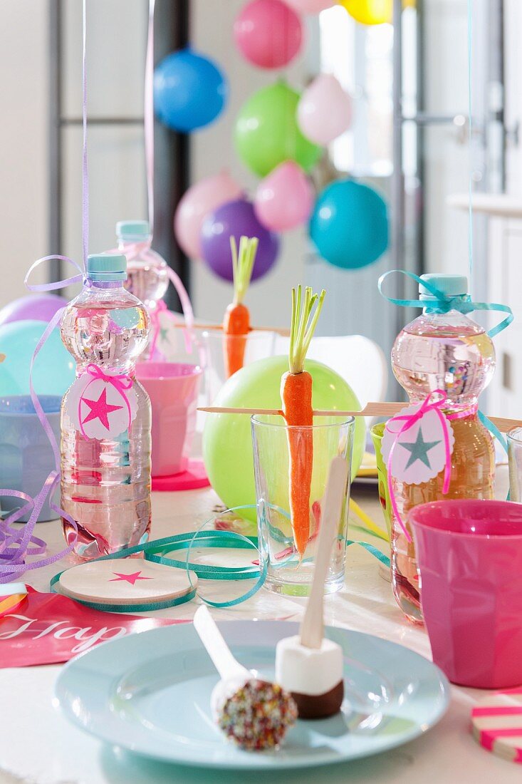 Süssigkeiten, Karotten und Wasserflaschen auf einem Geburtstagstisch