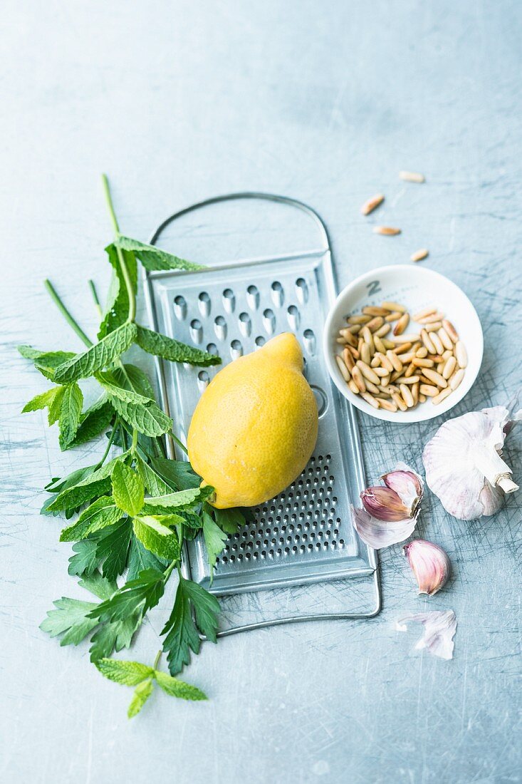 An arrangement of mint, lemon, pine nuts and garlic