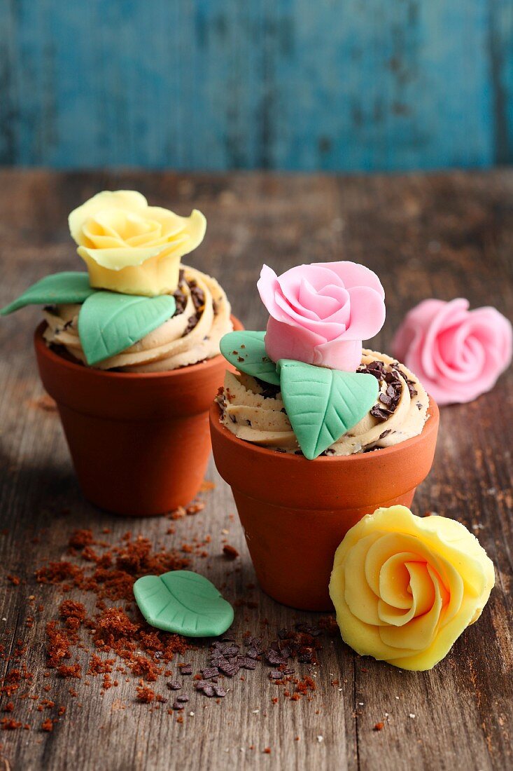 Muffins mit Karamell-Frosting und Fondant-Rosen im Blumentopf