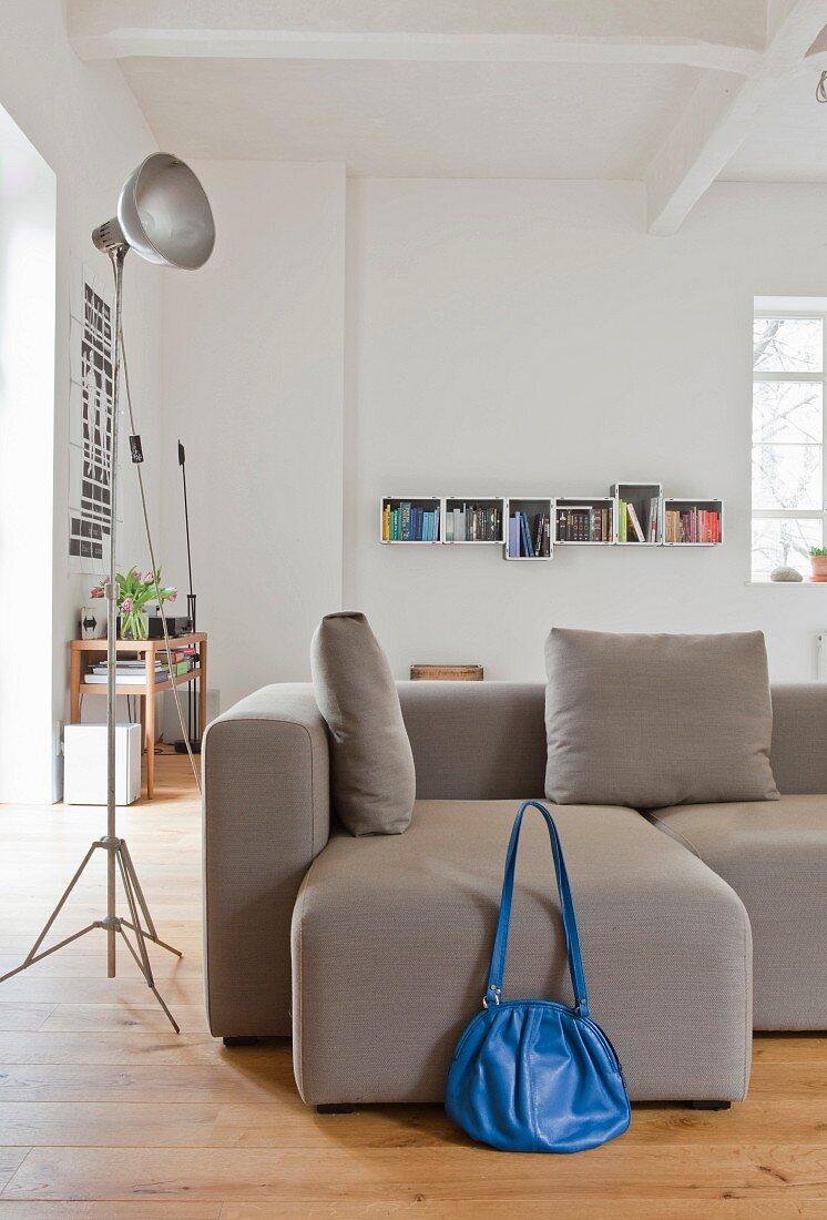 Blaue Tasche vor grauem Sofa in urbanem Loft