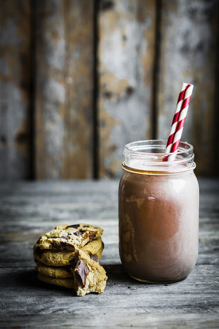 Chocolate milk in a jar with a straw with cookies next to it