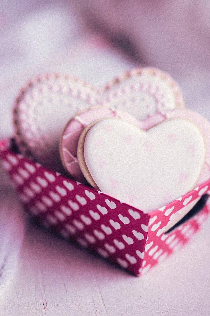 Pastel coloured heart-shaped biscuits in a paper box decorated with hearts