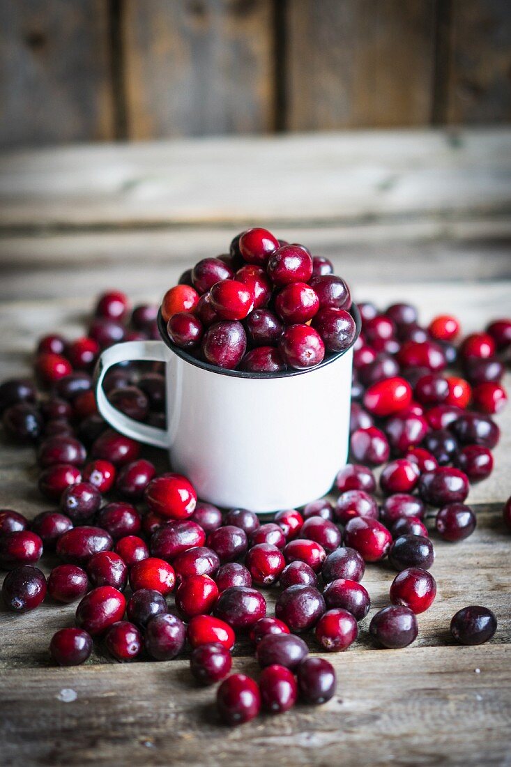 Cranberries in a mug and on a rustic wooden surface