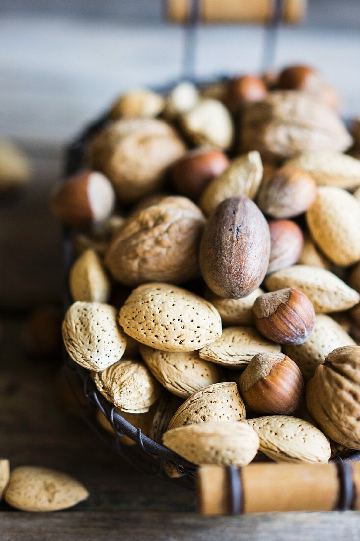 A nut mix in a basket on a rustic wooden surface