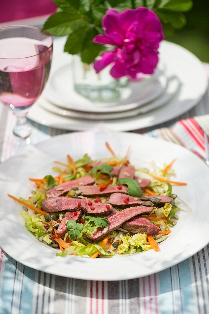 Asiatischer Rindfleischsalat mit Chili, Limetten und Koriander auf Tisch im Freien