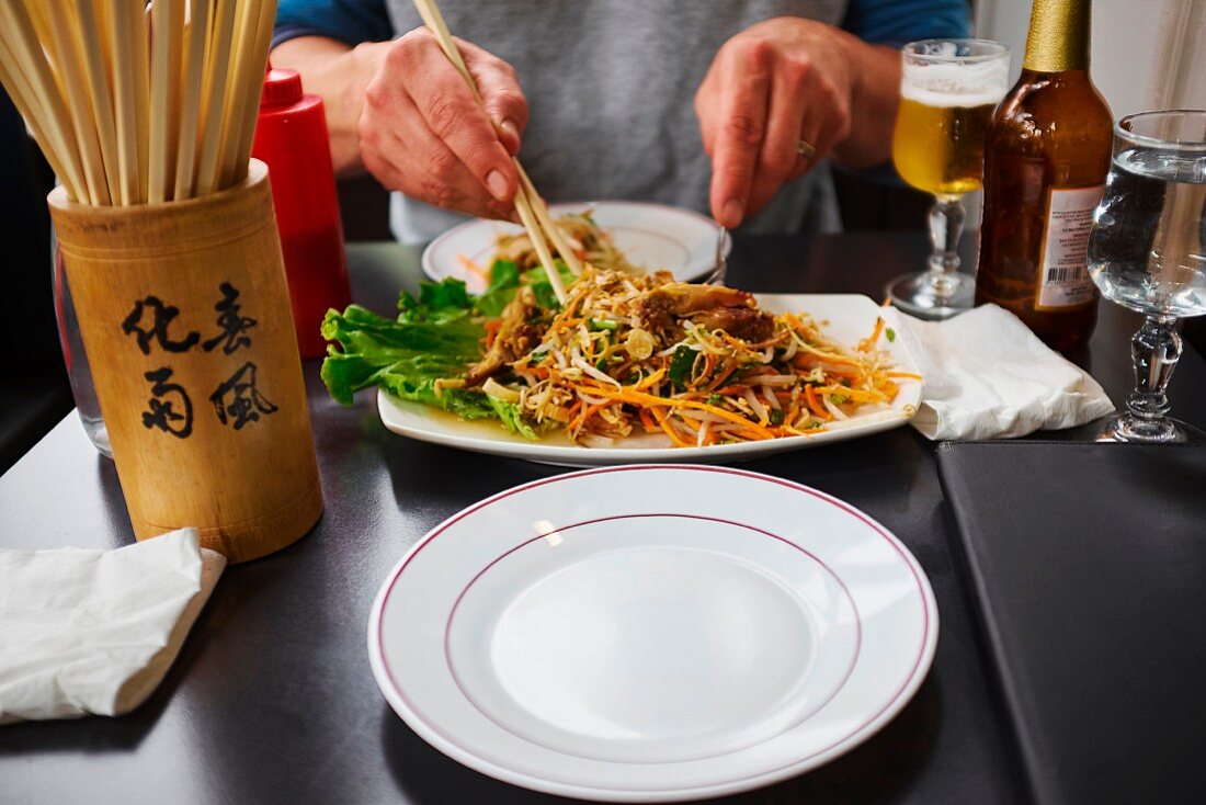 A person eating an Oriental noodle dish with chopsticks