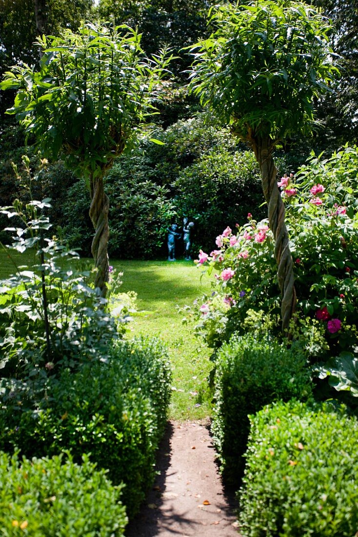 Lawn and two statues in well-tended summery garden