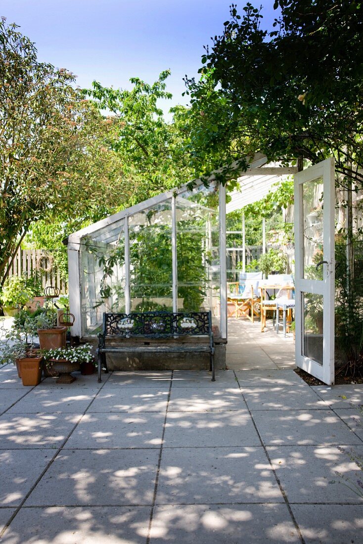 White-framed greenhouse on paved terrace