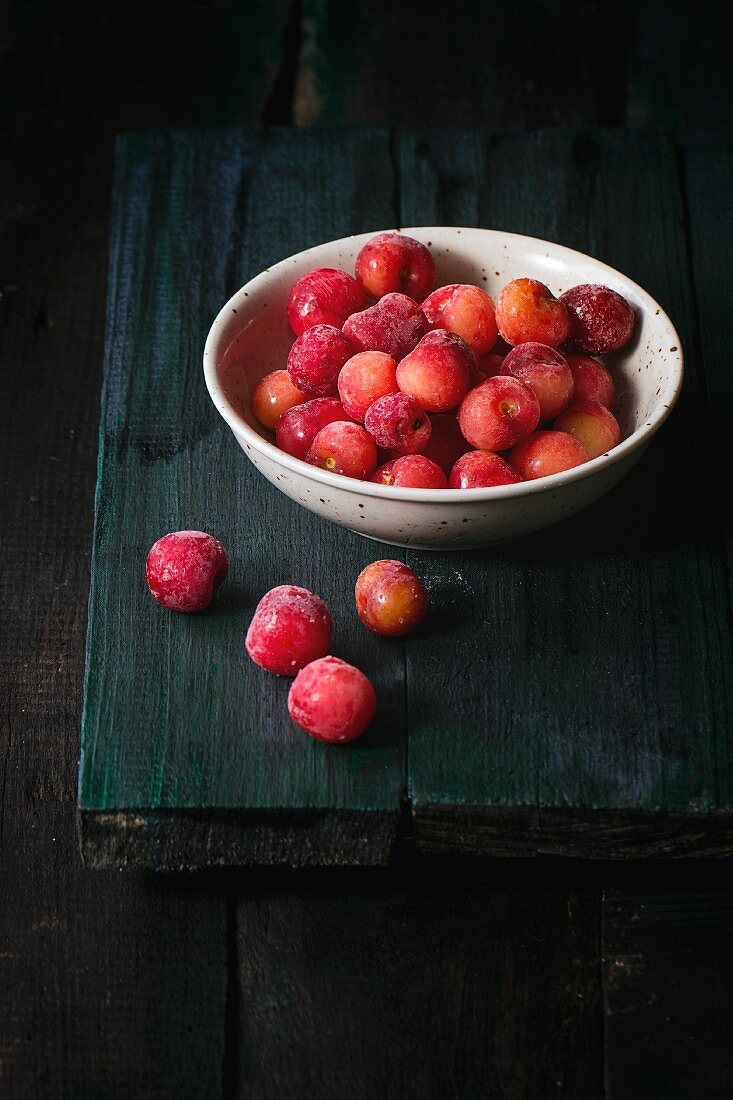 A bowl of frozen cherries on an old wooden table