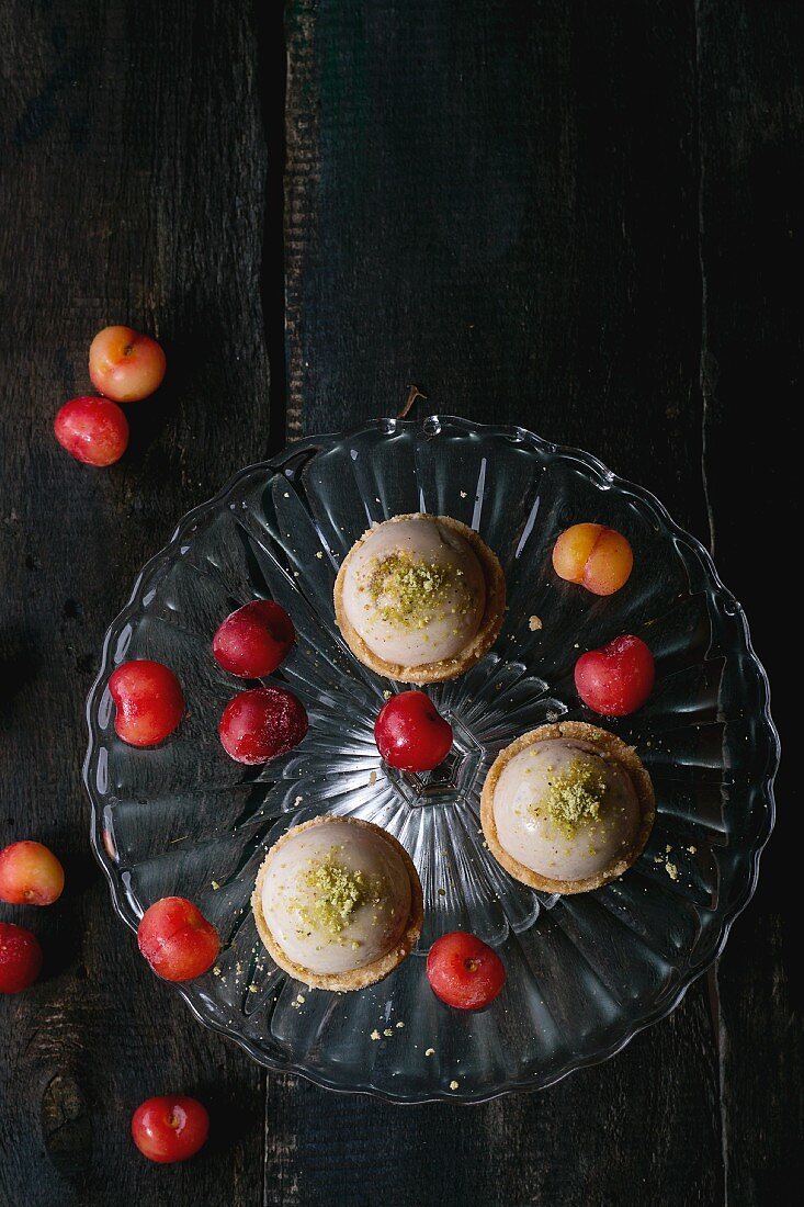 Shortcrust tartlets with pistachios and cherries on a vintage cake stand
