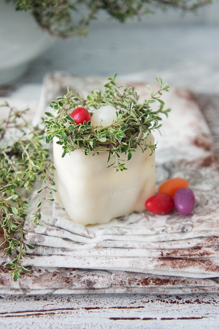 A petit four decorated with a nest, thyme and sugar eggs