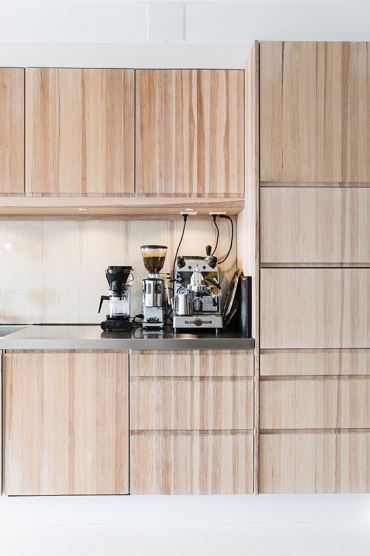 Fitted kitchen with pale wooden fronts, espresso machine, coffee mill and percolator on worksurface