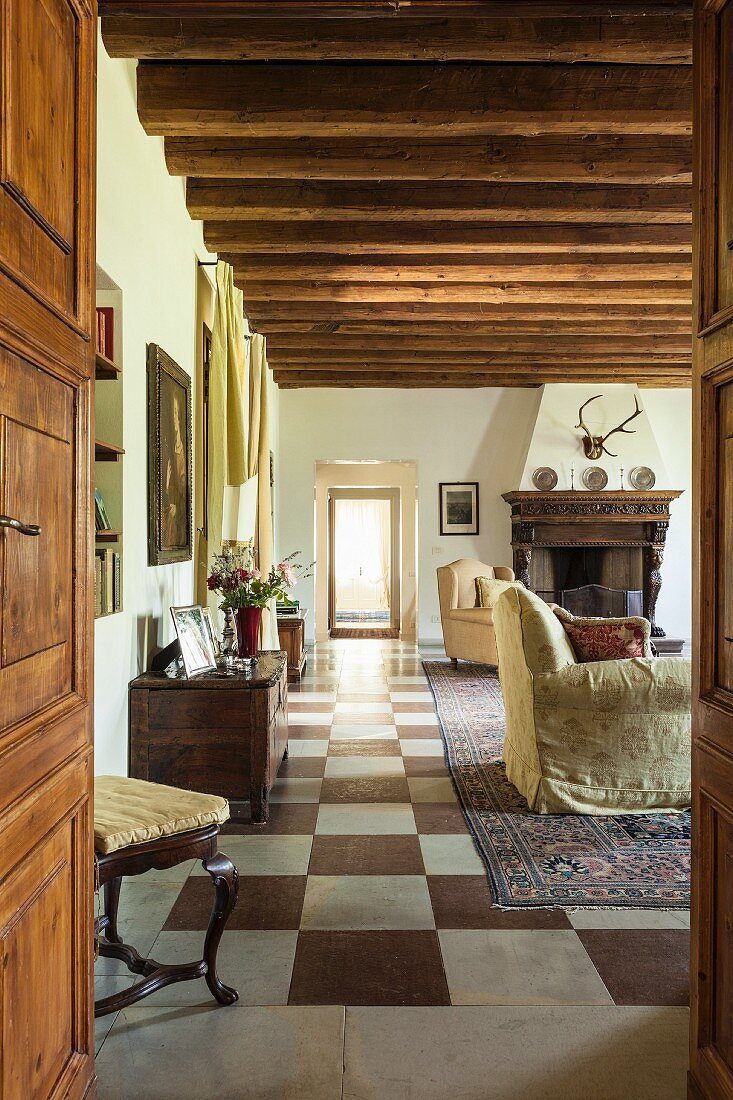 View through open door into lounge area with rustic wood-beamed ceiling and chequered floor