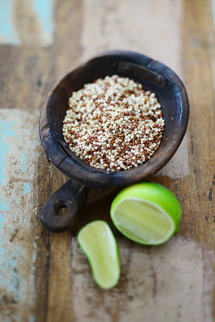 Bunter Quinoa in Holzschale, daneben Limette