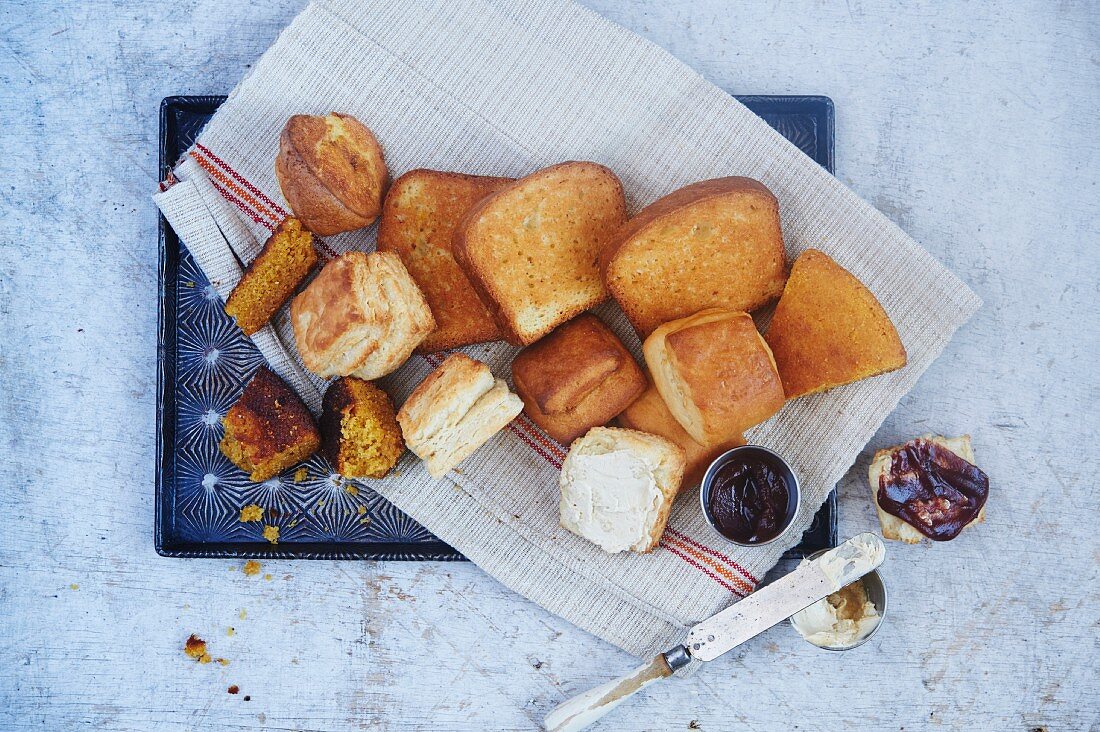 Verschiedene Brote und Brötchen mit Butter und Marmelade (Draufsicht)